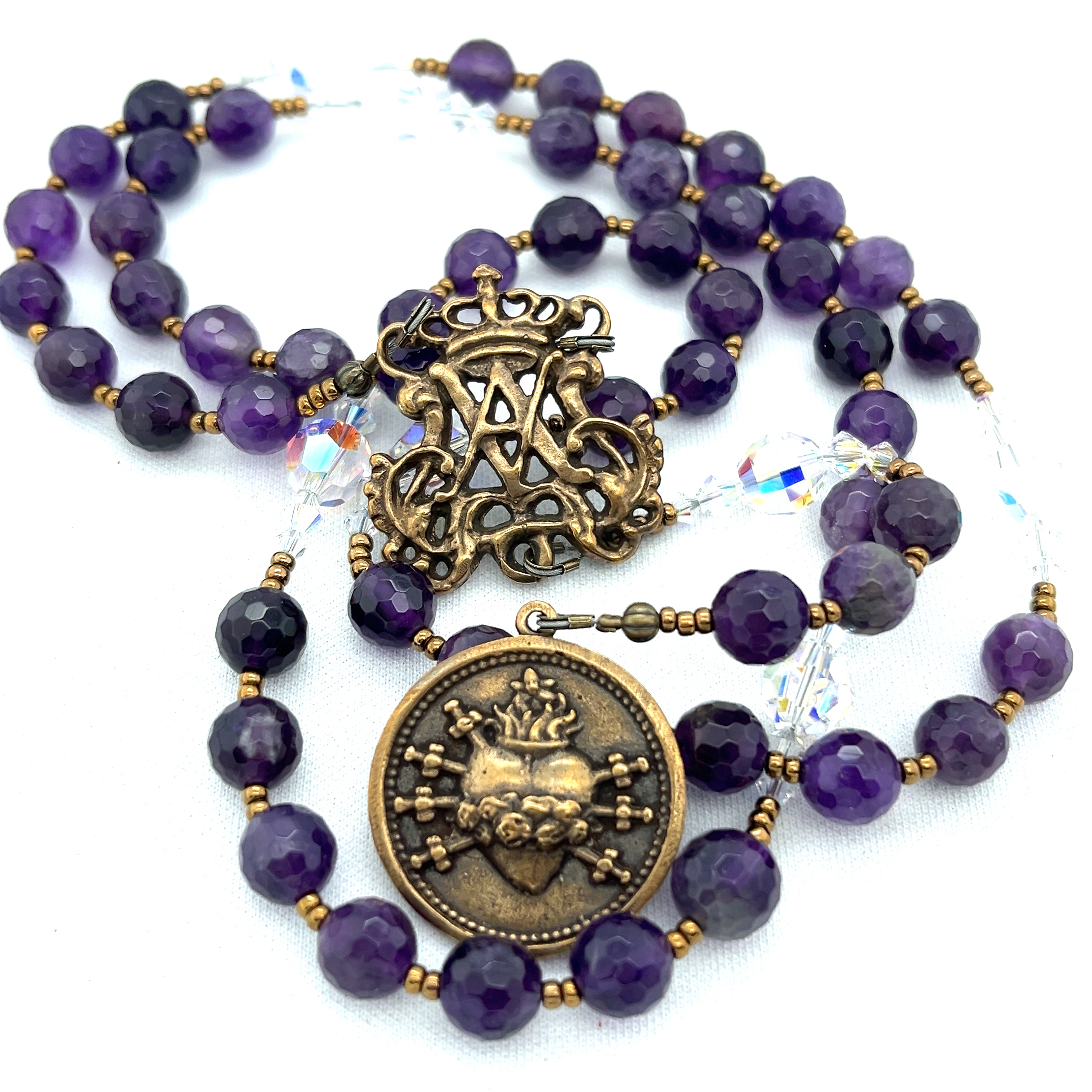 A bronze rosary center featuring Mary's heart and the seven swords that pierced it. Amethyst beads in the chaplet area deep purple.