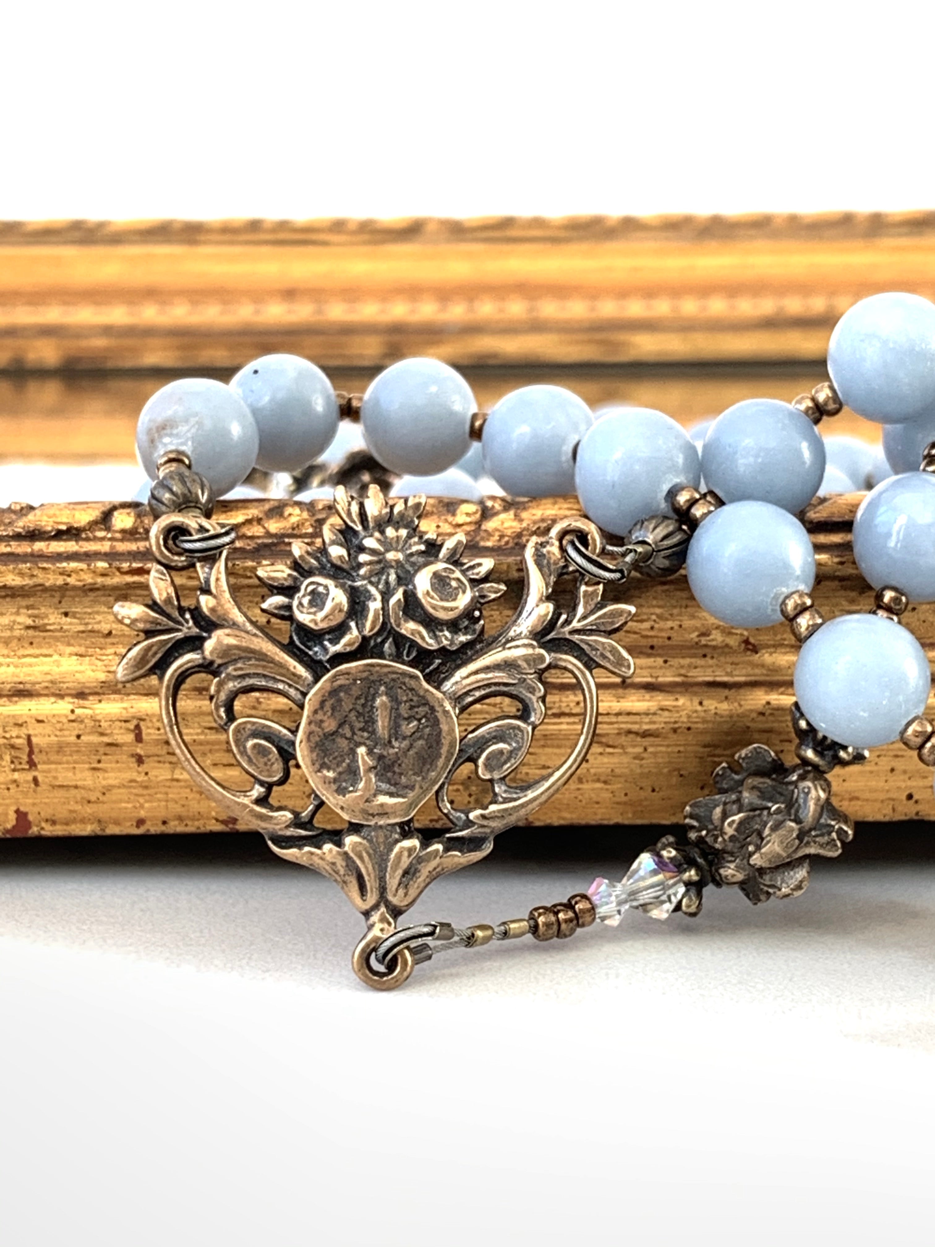 Lourdes center (bronze) with rose beads and blue angel stone in the background.in th
