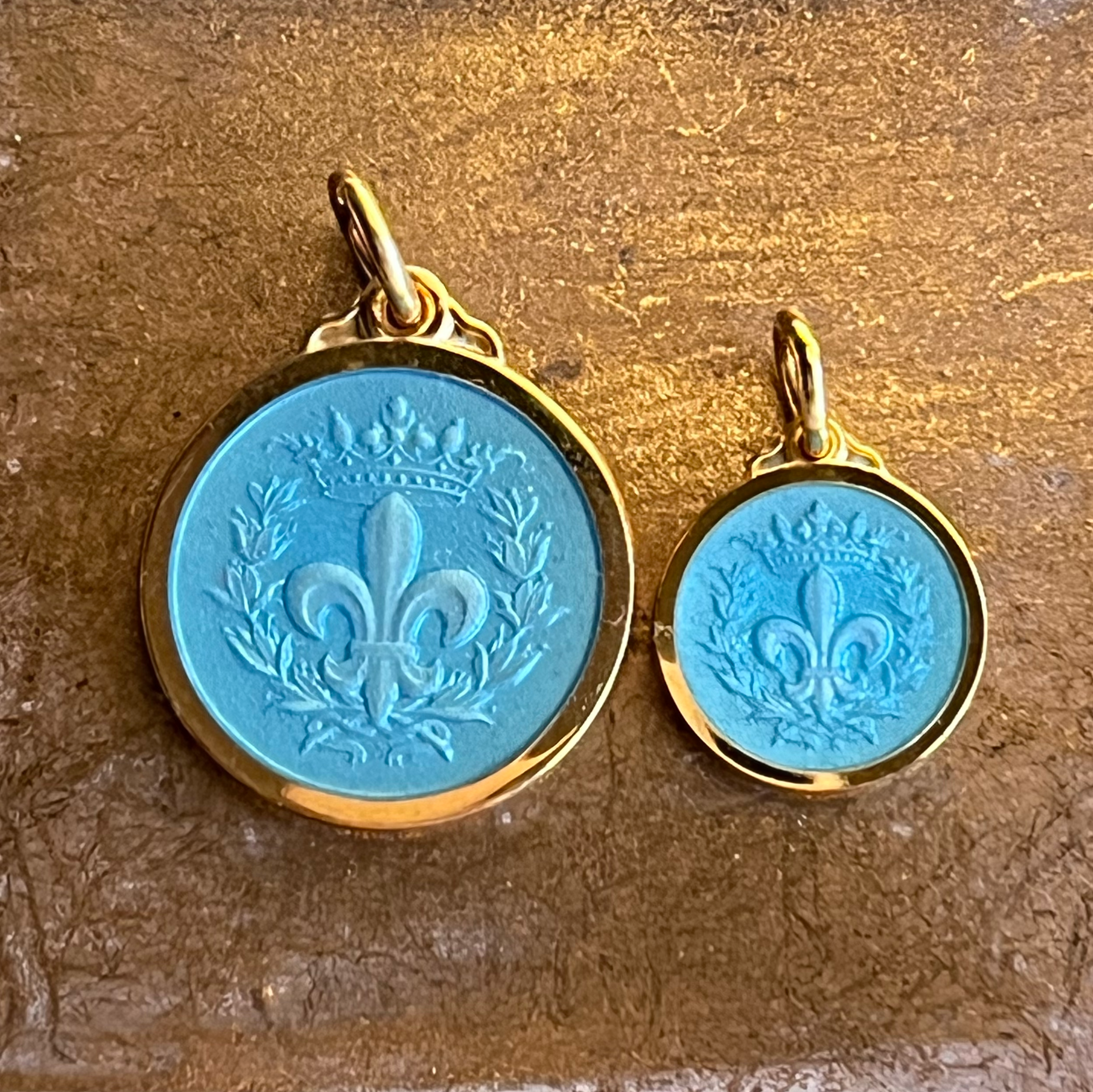 two 14 karat gold vermeil and aqua blue enamel fleur de lis pendants shown in two different sizes
