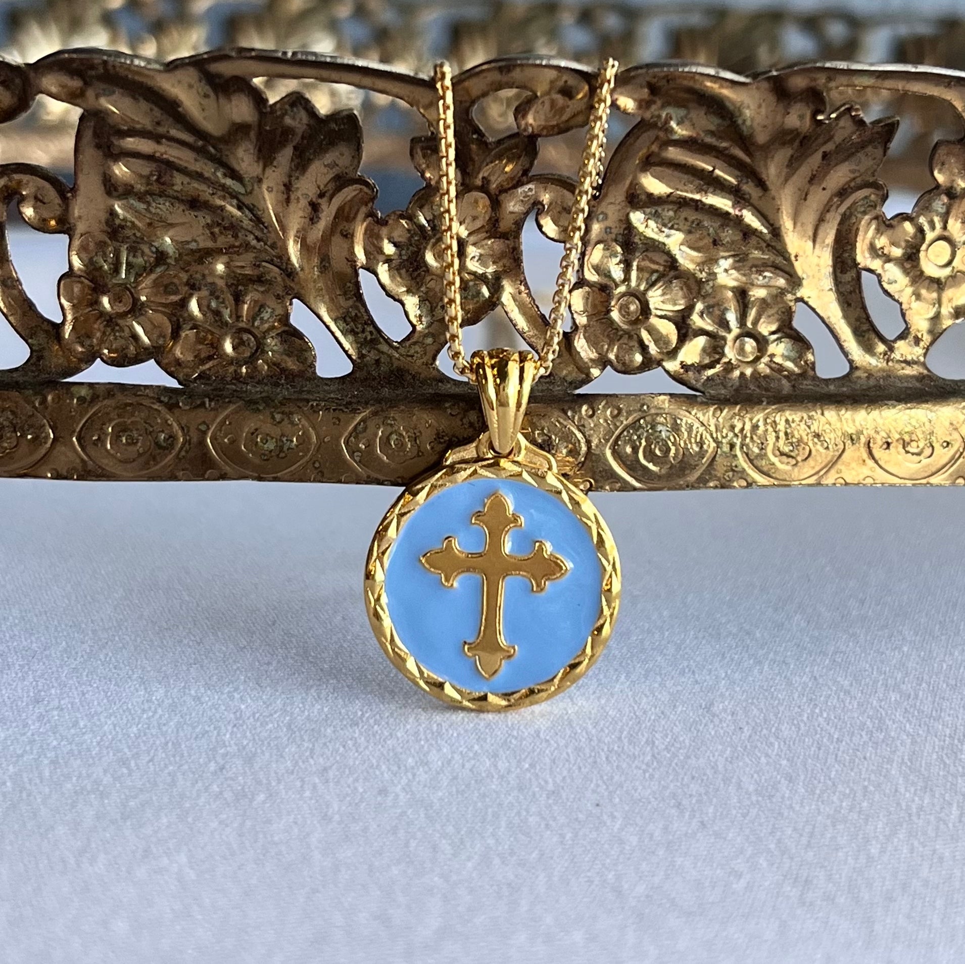 Gold cross surrounded by blue color on the back of the gold vermeil sacred heart pendant