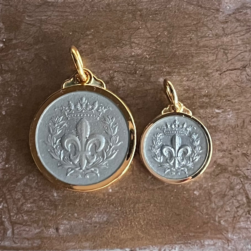 Two sizes of fleur de lis necklace pendants shown in 14 karat gold vermeil and grey enamel