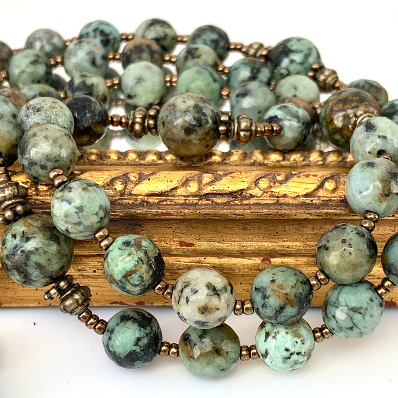 close up picture of african turquoise jaspar rosary beads and bronze spacers on single decade rosary with Gothic crucifix and Holy Spirit medal.