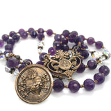 A bronze rosary center featuring Mary's heart and the seven swords that pierced it..  Beads in the background area purple.