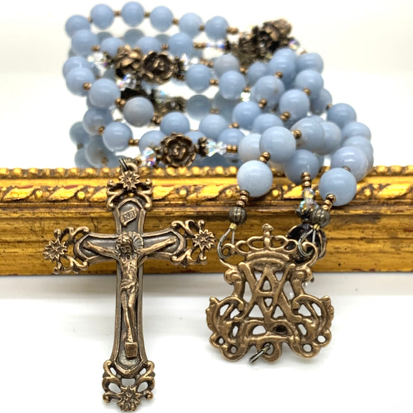 Scroll crucifix on left, Auspice Maria center on right, and angelstone rosary beads in background.