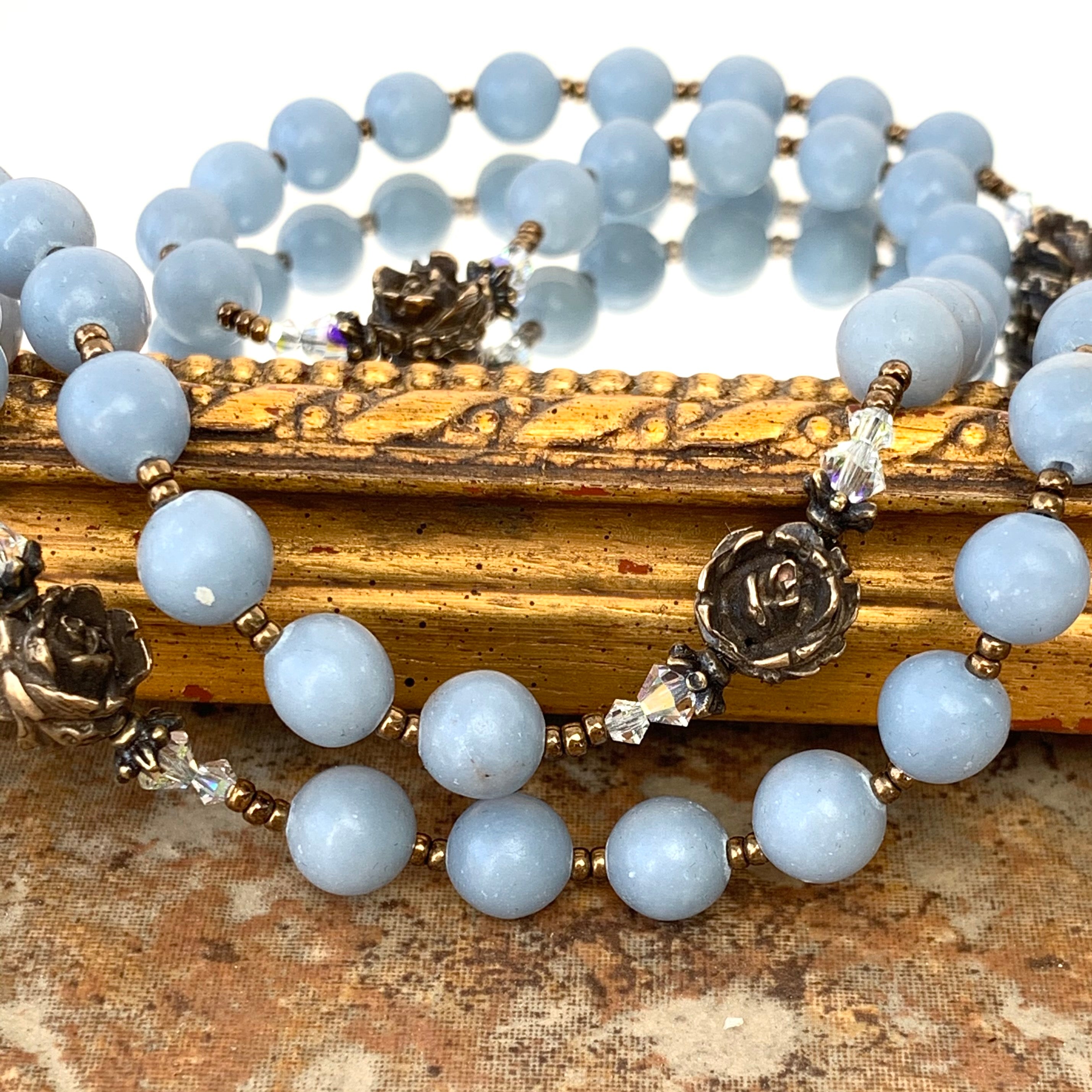 Angelite rosary beads along with bronze rose and Swarovski crystal spacers.