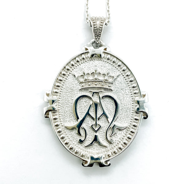 Silver Necklace pendant hanging on a chain showing emblem of Auspice Maria with a crown at the top of the intertwined A and M.