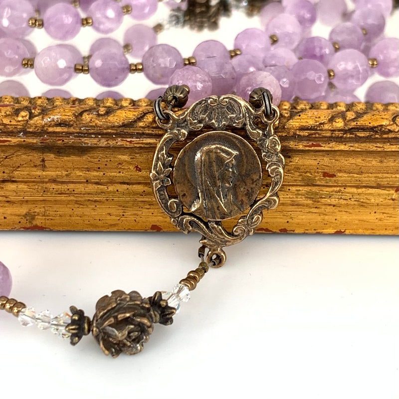 Graceful bronze center with profile of our lady.  Amethyst rosary beads in background.  Pretty bronze rose bead and crystal spacers.