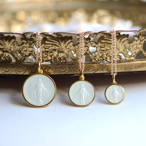 3 gold miraculous medal pendants with white enamel.  The three pendants vary in size.