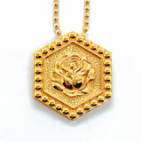Gold hexagonal pendant hung on a bead chain.  The pendant features a rose in the center, and raised dots around the border.